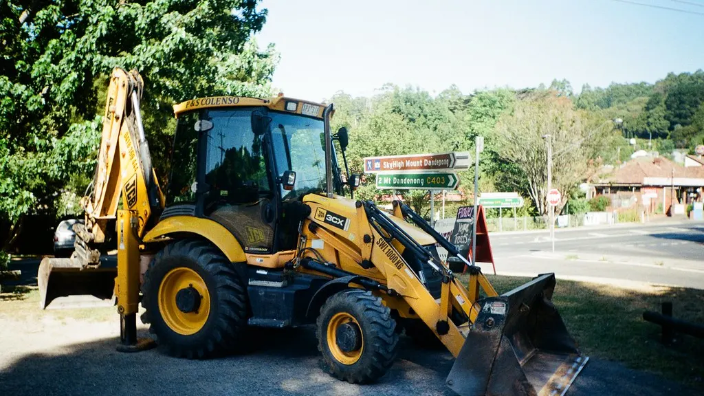 A yellow JCB backhoe loader parked on a roadside