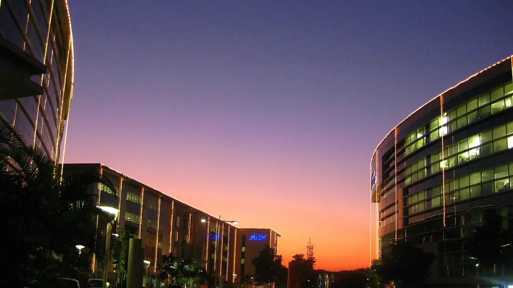 Glass office buildings in Bengaluru against an orange evening sky