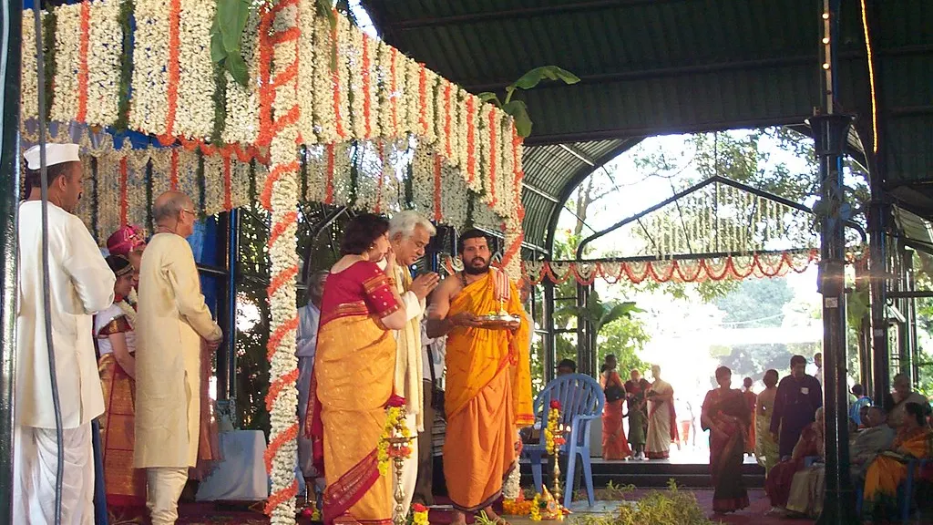 A wedding ceremony under a mandap decorated with marigold garlands